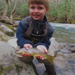 Young man shows his first trout on a fly